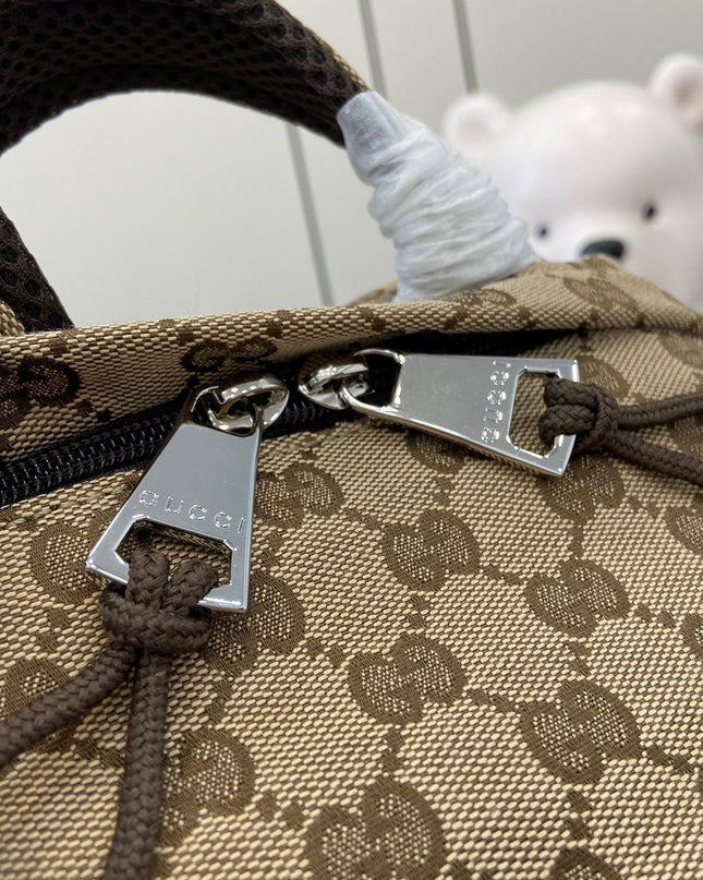 Close-up of a patterned bag with a visible brand tag, blurred background with a teddy bear.